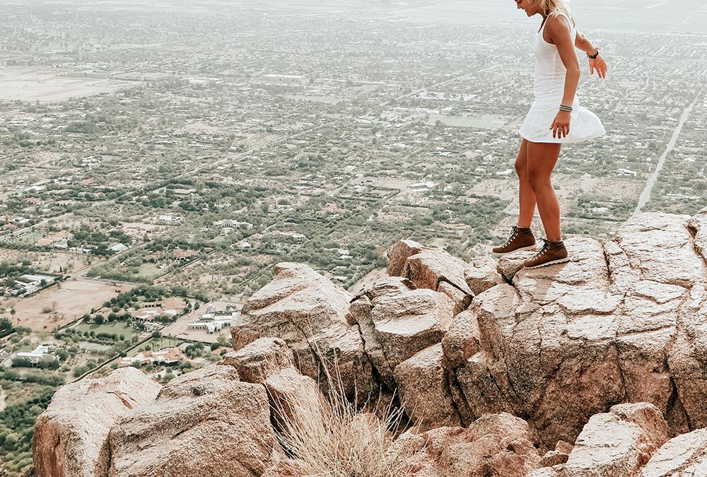 A woman hiking on a cliff overlooking a city