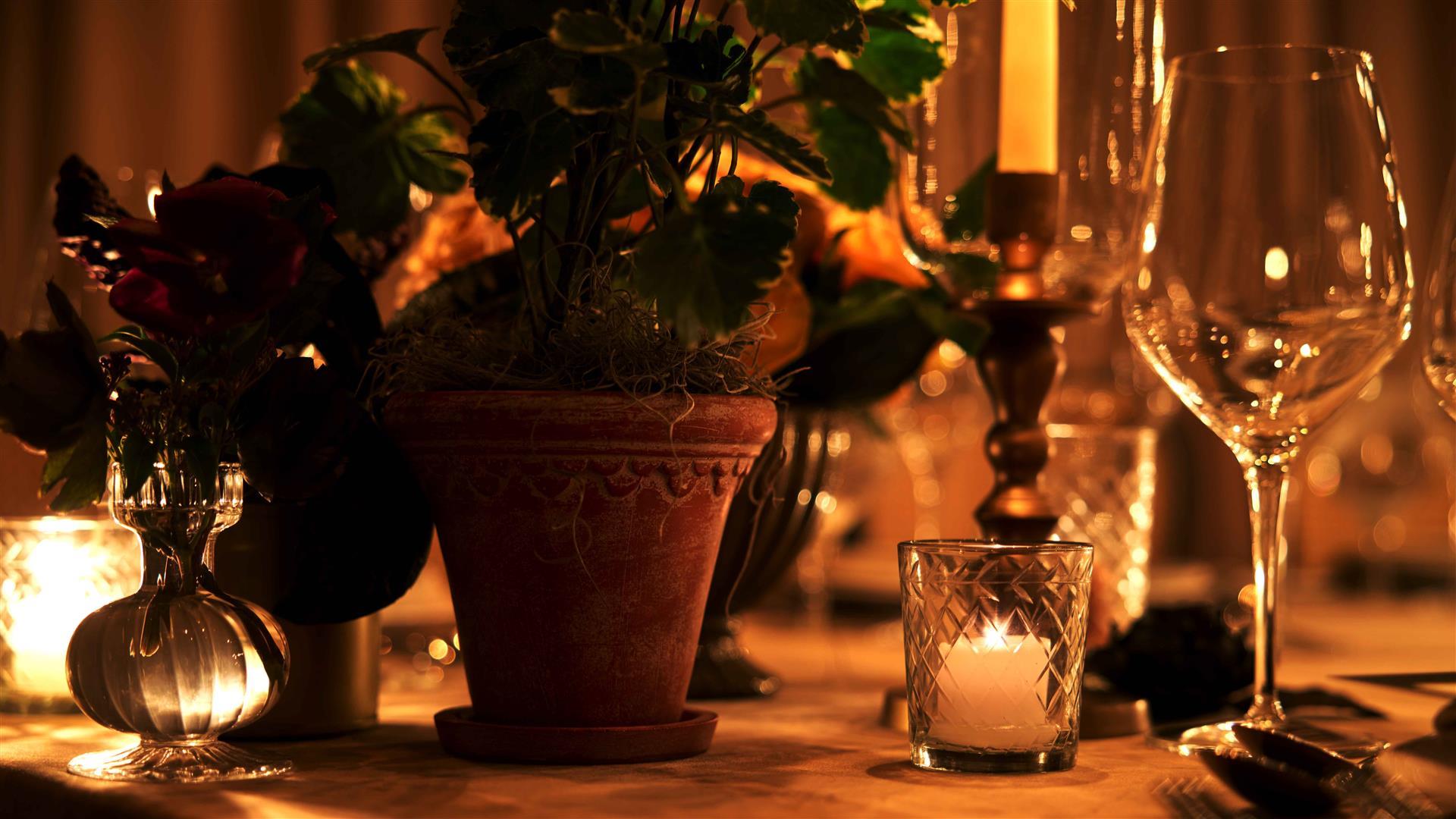 A Pot of Flowers alongside some Candles on a Table