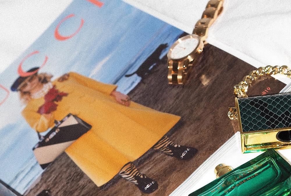 A Gucci magazine with a gold watch and some other luxury accesories