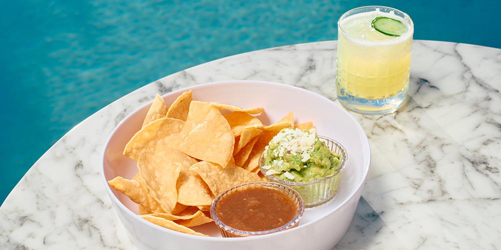 Chips with salsa and guacamole along with a glass of alcohol